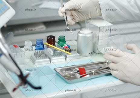 عکس پزشک در حال انجام کار و تجهیزات دندان پزشکی روی میز