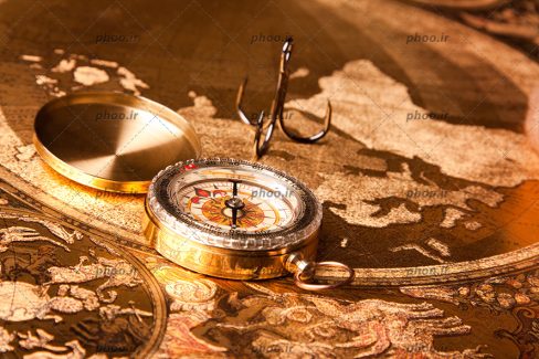 عکس با کیفیت قطب نما به رنگ طلایی قرار گرفته در پس زمینه طلایی رنگ