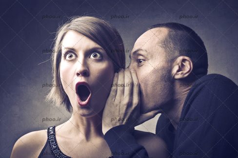 عکس با کیفیت مرد در حال صحبت در گوش زن و زن متعجب از صحبت های مرد