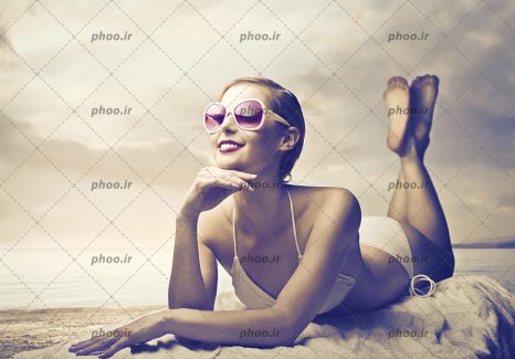 عکس با کیفیت زن با لباس شنا و عینک دودی در ساحل