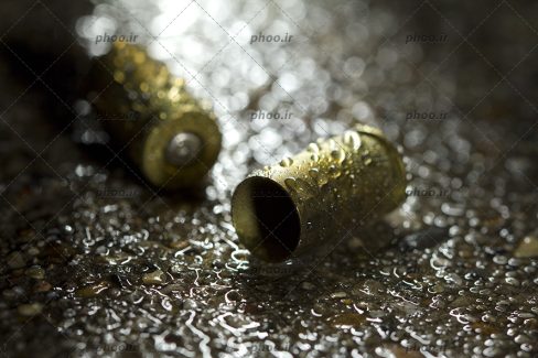 عکس با کیفیت پوکه فشنگ افتاده بر روی زمین باران خورده