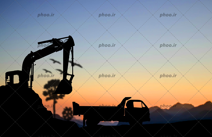 عکس با کیفیت ماشین خاکبرداری در حال ریختن خاک در کامیون و آسمان در حال غروب کردن