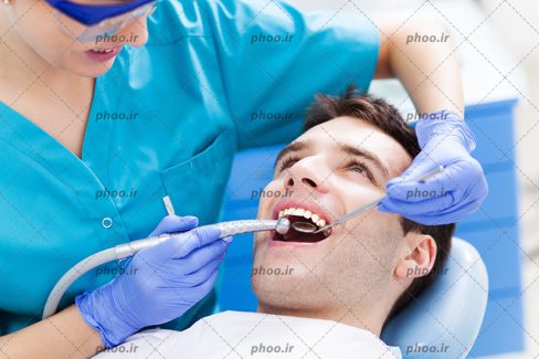 عکس بیمار مرد و دندانپزشک درحال مداوا او