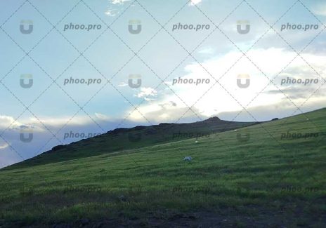 تپه‌های سرسبز در دل طبیعت و آسمان نیمه‌ابری