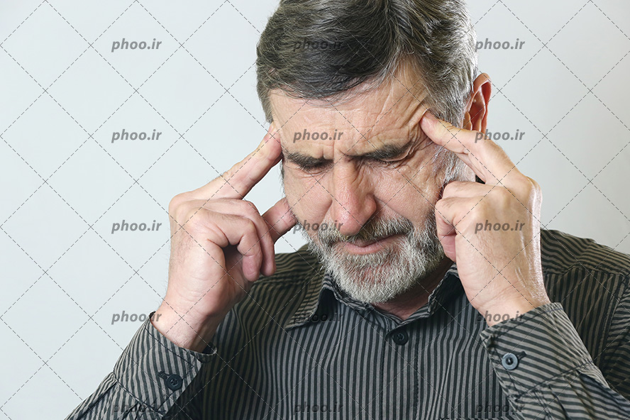 عکس با کیفیت پیر مرد دارای میگرن و سردرد و گرفتن هردو دست در کنار صورت خود