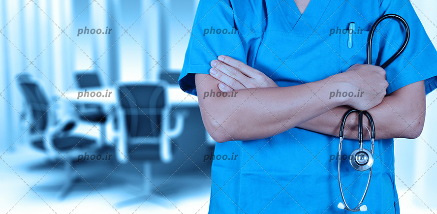 عکس با کیفیت پزشک با روپوش آبی و دست به سینه ایستاده و استتوسکوپ در دستش