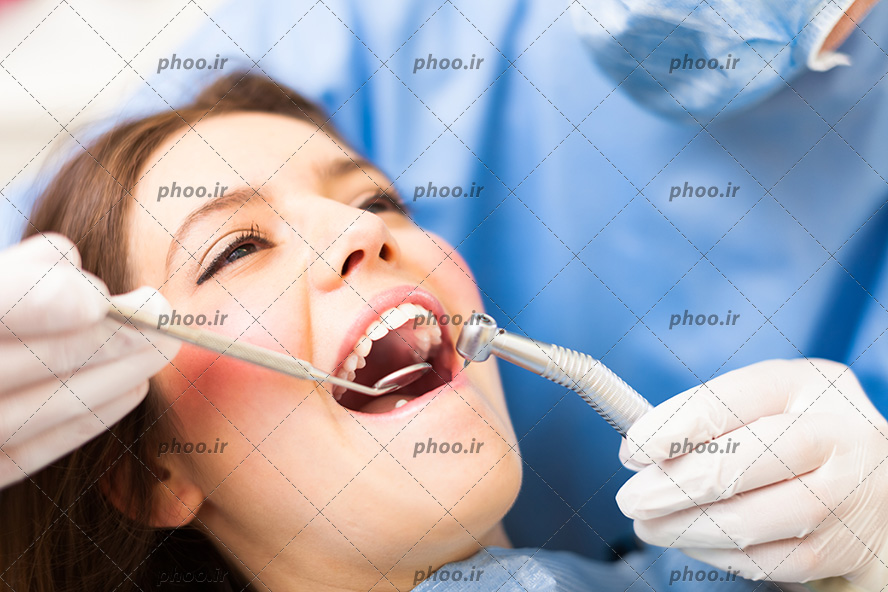 عکس با کیفیت دندان پزشک در حال معاینه دندان های زن با آینه گرد کوچک