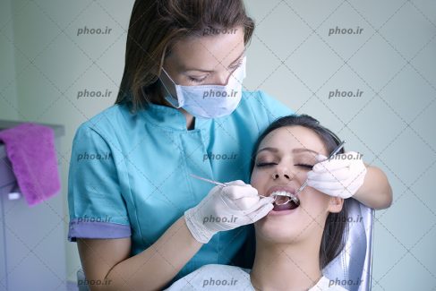 عکس با کیفیت دندان پزشک در حال معاینه دندان های زن زیبا به کمک آینه مقعر دندانپزشکی