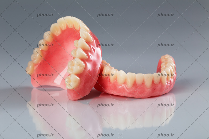 عکس با کیفیت دو دندان مصنوعی در پس زمینه خاکستری