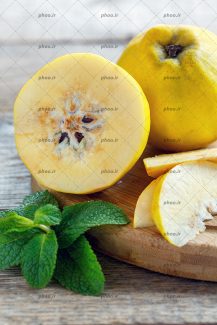 عکس میوه گلابی و برش هایی از آن روی تخته چوبی