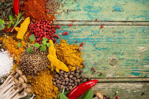 عکس ادویه های رنگارنگ برای پخت و پز در پس زمینه چوبی