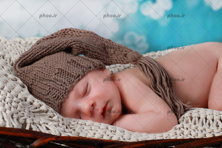 عکس نوزاد شیرین خوابیده روی پتو با کلاه بافتنی قهوه ای