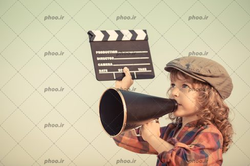 عکس با کیفیت کودکی که تخته کفگیر و بلندگوی قدیمی در دست دارد