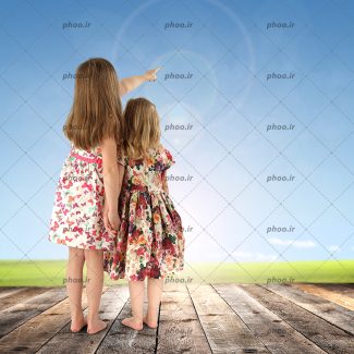عکس با کیفیت دو دختر ایستاده روی تخته چوبی در حال اشاره به آسمان آبی