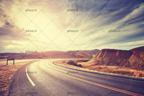 عکس جاده ای در بیابان در پس زمینه آسمان ابری