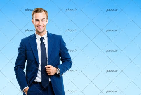 عکس مرد خوش تیپ با لبخند و کت شلوار و کروات در پس زمینه آبی