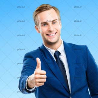 عکس مرد با لبخند و کت و کروات در حال نشان دادن علامت لایک با دست در پس زمینه آبی