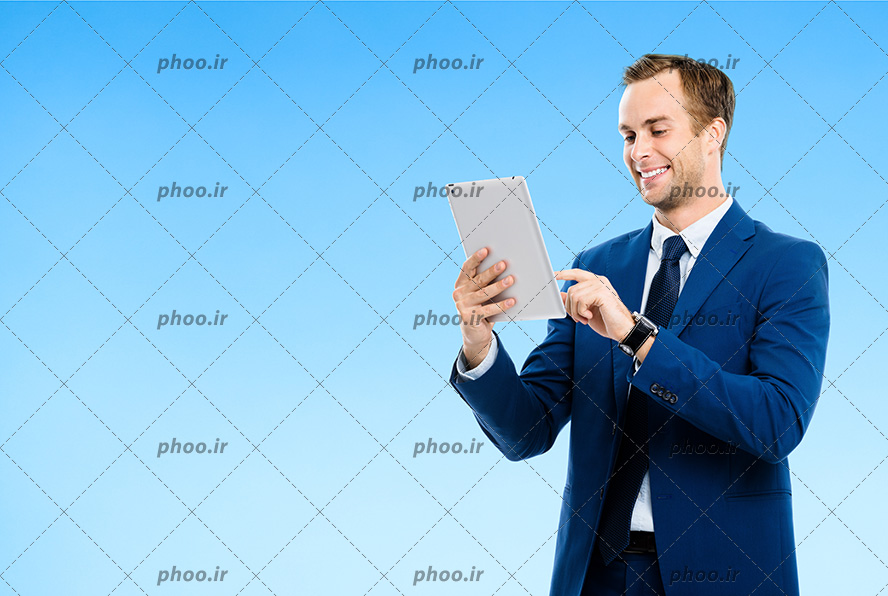 عکس مرد خوشحال با کت شلوار در حال کار کردن با تبلت در پس زمینه آبی