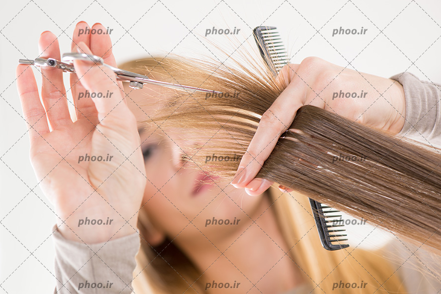 عکس آرایشگر زن ایستاده درحال کوتاه کردن موها
