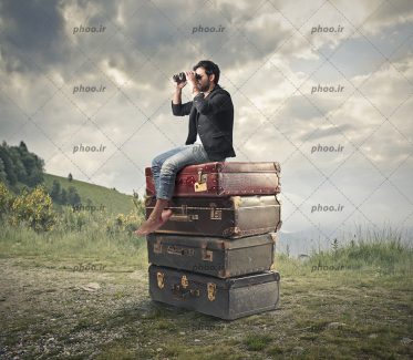 عکس با کیفیت مرد جوان نشسته بر روی تعدادی چمدان