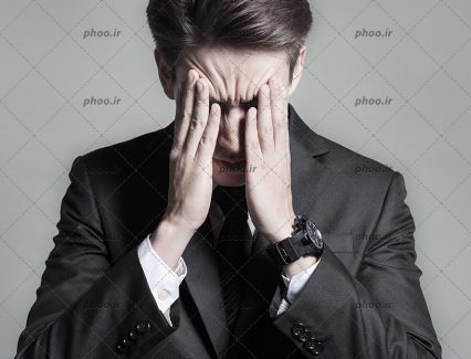 عکس با کیفیت مرد عصبانی با کت مشکی در حال فشار دادن سر خود با دست