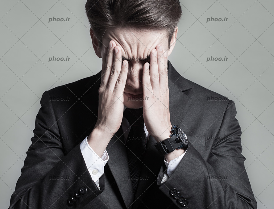 عکس با کیفیت مرد عصبانی با کت مشکی در حال فشار دادن سر خود با دست