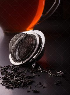 عکس صافی چای با چای خشک در کنار فنجان چای در پس زمینه مشکی