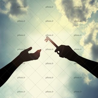 عکس کلید در دست در حال تحویل دادن به دیگری در برابر آسمان ابری