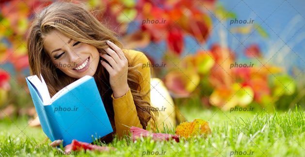 عکس با کیفیت دختر زیبا در حال کتاب خواندن در پارک با برگ های پاییزی