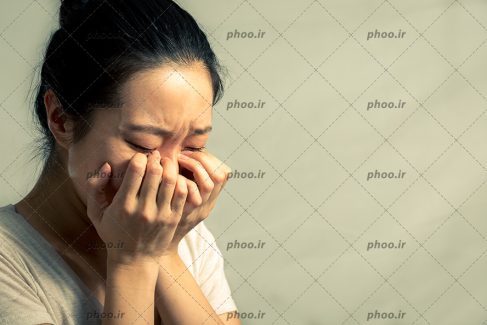 عکس با کیفیت خانم جوان با دست ها روی صورت در حال گریه کردن