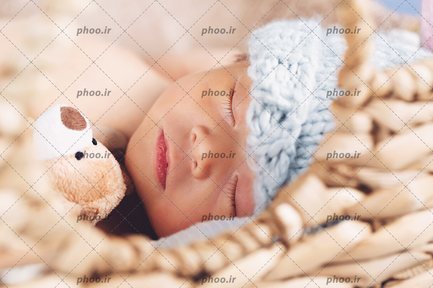 عکس نوزاد خواب با کلاه در کنار عروسک از نمای نزدیک