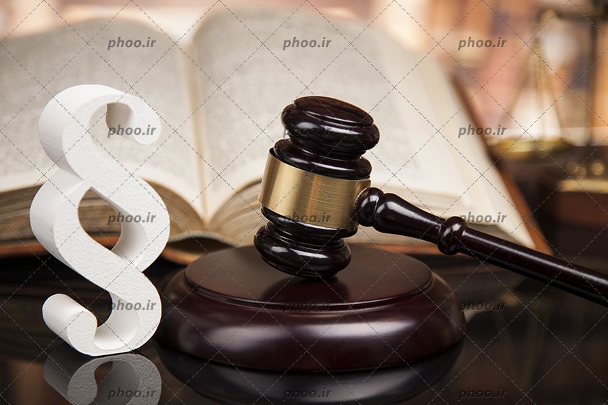 عکس چکش قاضی در کنار یک کتاب باز روی میز