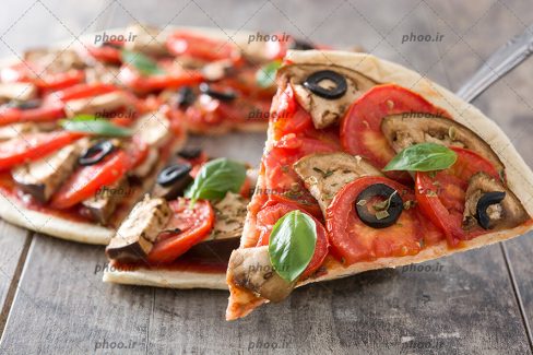 عکس پیتزا و یک برش از آن در پس زمینه چوبی