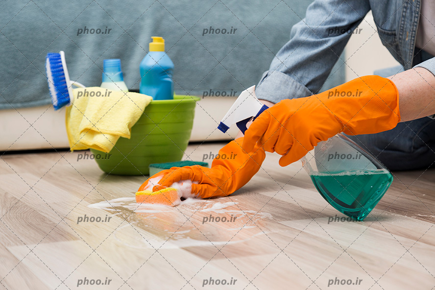 عکس با کیفیت زن در حال تمیز کردن پارکت چوبی و مواد شوینده داخل سطل