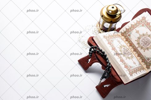 عکس با کیفیت قرآن کریم بر روی رحل و تسبیح و فانوس طلایی در کنارش