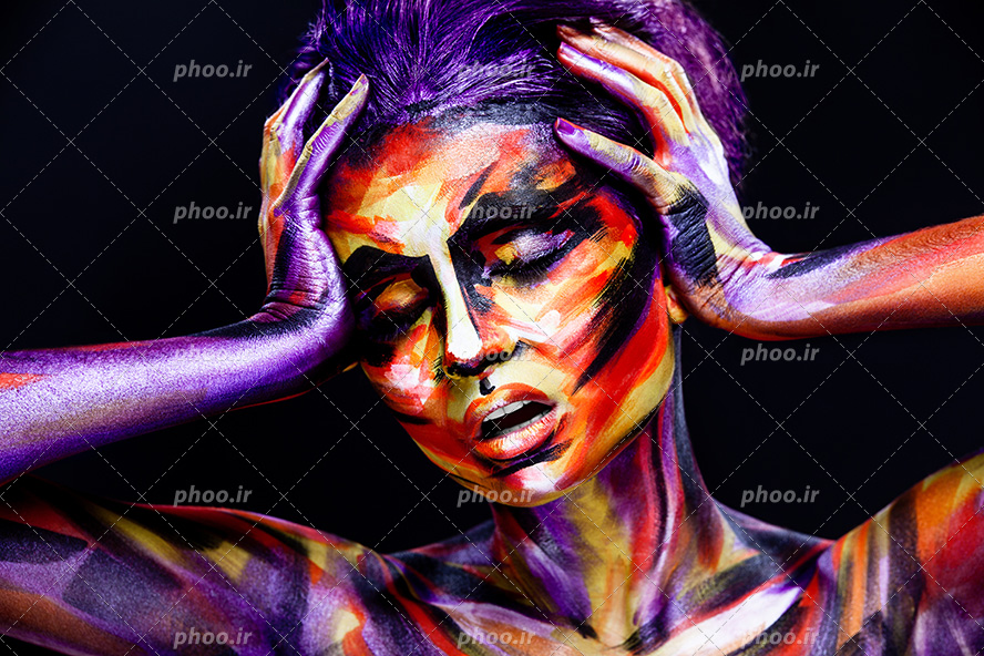 عکس با کیفیت زن با ژست دو دست بر روی صورت و چهره نقاشی شده با رنگ های زیبا و پس زمینه به رنگ مشکی