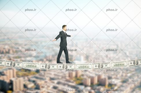 عکس تاجری که روی خط اسکناس دلار بالای شهر راه می‌رود