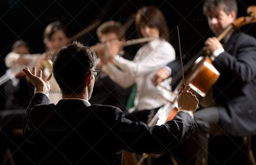 عکس رهبر گروه در مقابل گروه ارکستر در حال اجرا