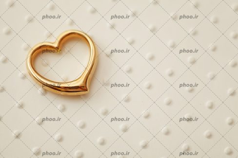 عکس با کیفیت حلقه طلایی به شکل قلب در پس زمینه سفید