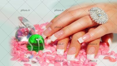 عکس با کیفیت دست خانم با انگشتر نقره ای و ناخن های مانیکور شده در پس زمینه سفید
