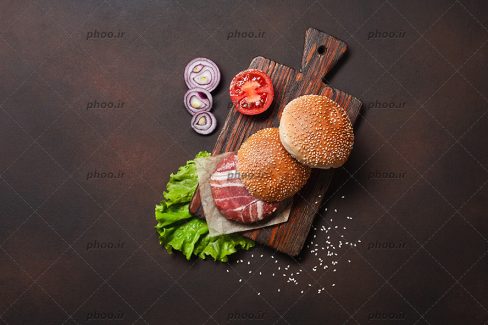 عکس ساندویچ با نون تست و سبزی ها و گوشت در ظرف چوبی با زمینه قهوه ای