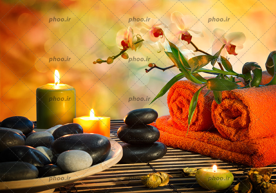 عکس سنگ ، شمع و حوله روی میز در پس زمینه محو