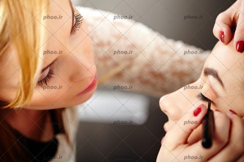 عکس آرایشگر در حال آرایش چشم در سالن زیبایی
