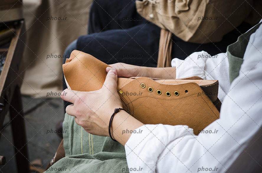 عکس کفاش در حال کار و یک کفش در دست
