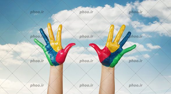 عکس دست های رنگی بچه در پس زمینه آسمان ابری