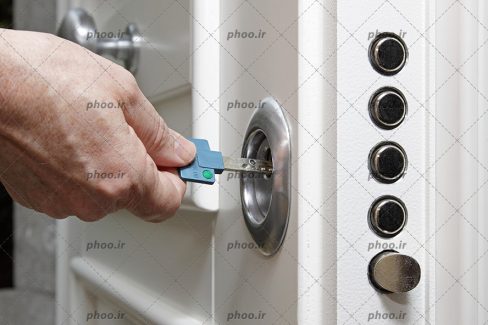 دست مرد درحال بستن یا باز کردن در چوبی سفید با کلید