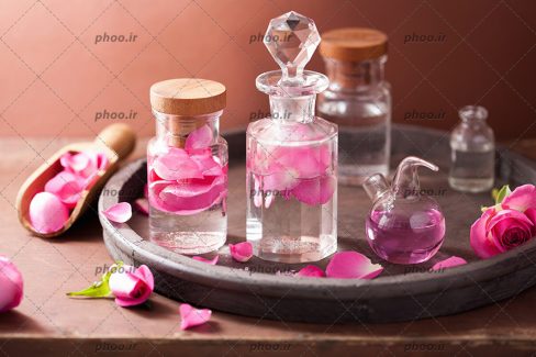 عکس کیمیا و مجموعه ای آروماتراپی با گل رز و بطری شیشه ای روی سینی