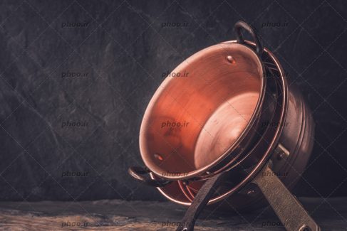 عکس ظروف آشپزخانه مسی در پس زمینه مشکی