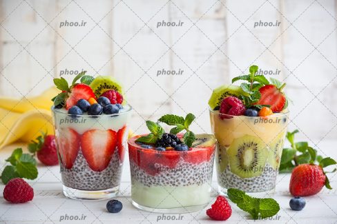 عکس سه فنجان دسر میوه و میوه های روی زمین از نمای نزدیک