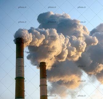 عکس با کیفیت دودکش های یک کارخانه با دود هایی که با آسمان می رود